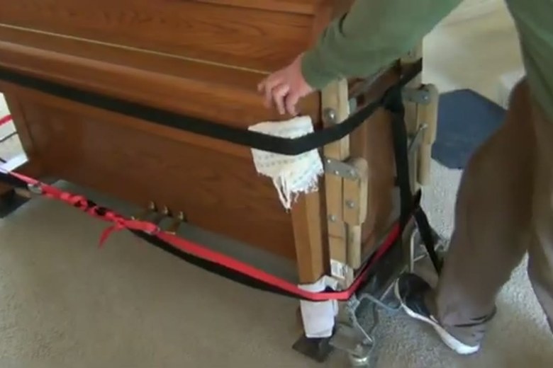 An upright piano strapped and ready to roll